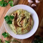 A bowl of parsley hummus sprinkled with paprika.