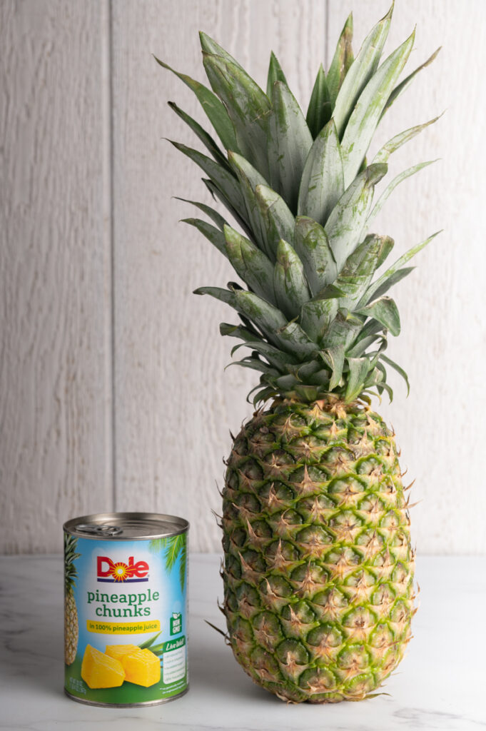 A can of pineapple and a fresh pineapple.