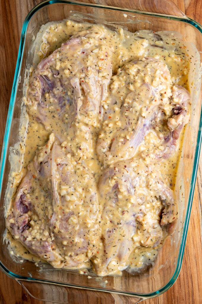 Chicken breasts marinating in a baking sheet.