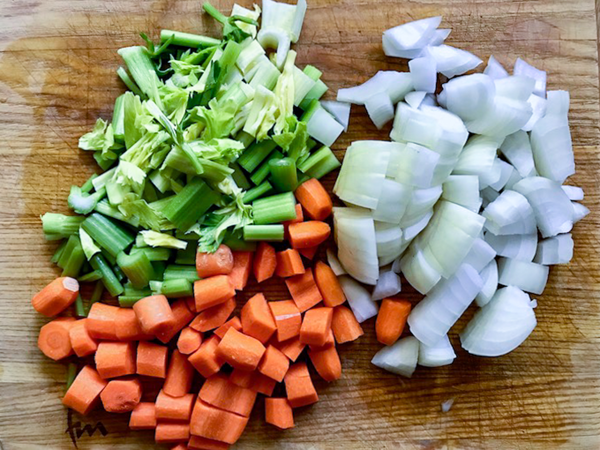 Chopped celery, onions, and carrots on a cutting board.