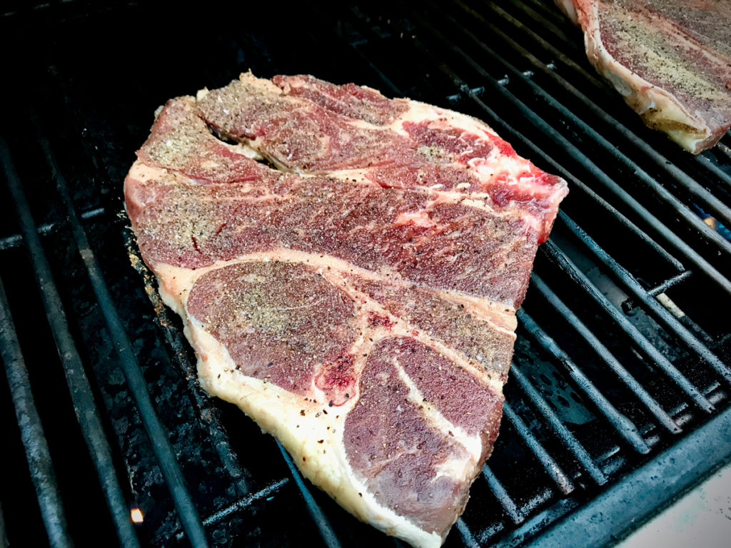 Placing chuck steak on a grill.
