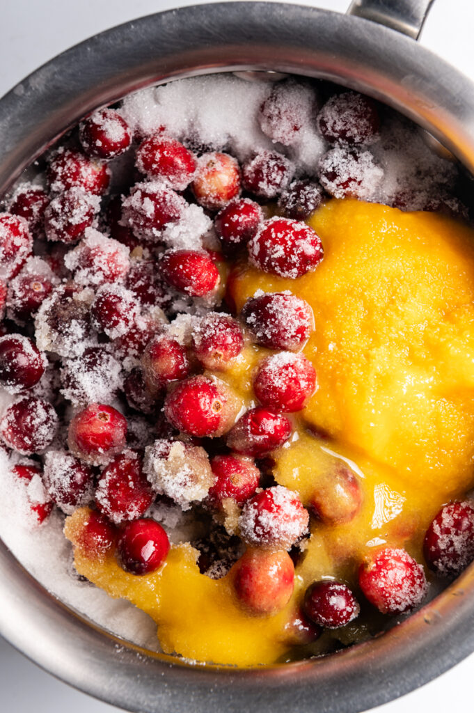 Cranberries, sugar, and orange juice in a pot.