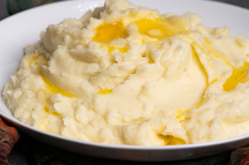Butter melting on top of a pile of mashed potatoes.
