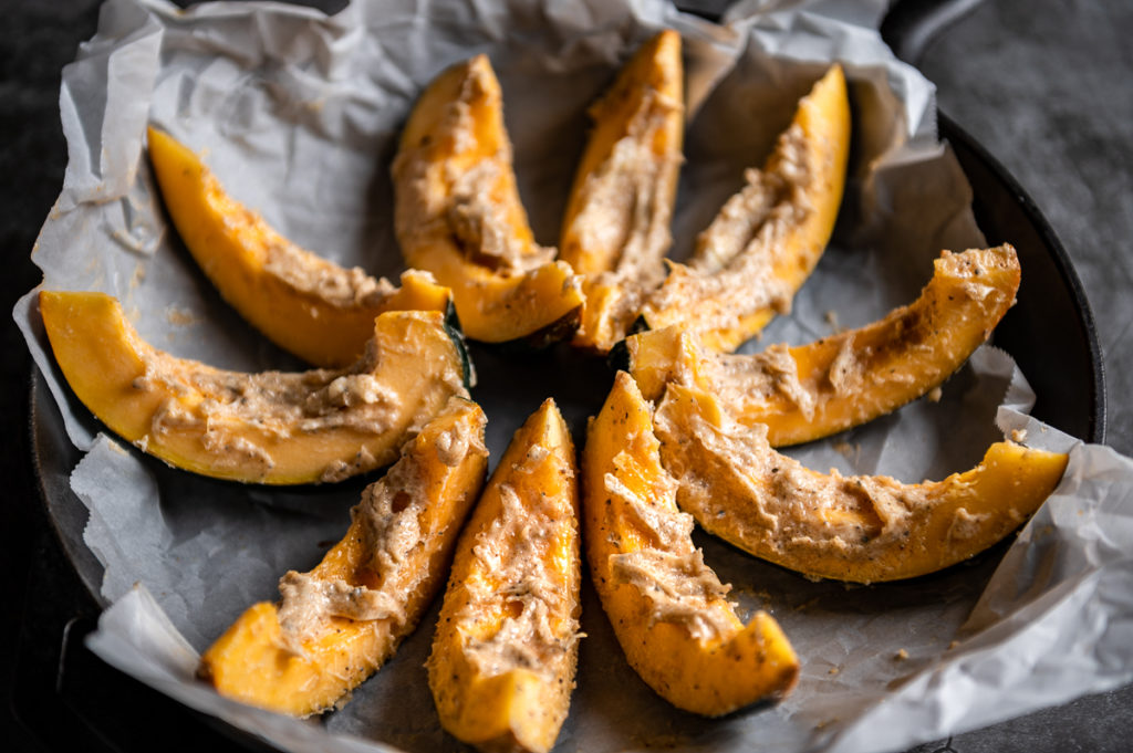 Acorn squash wedges spread with spiced butter in a cast iron skillet.