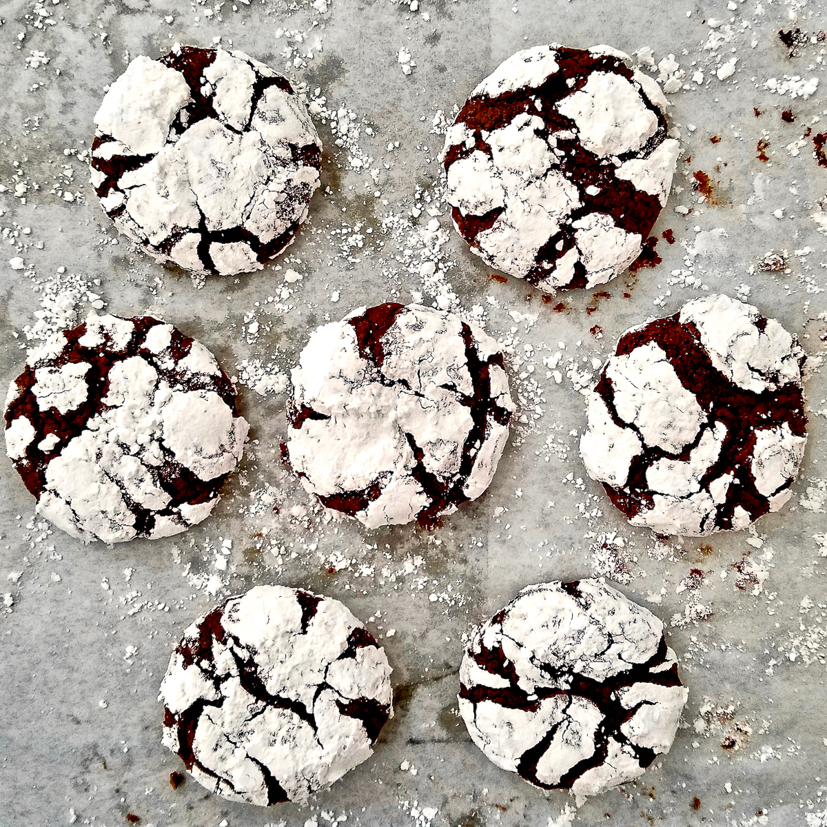 Seven crinkle cookies on a baking sheet.