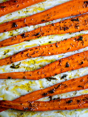 Roasted carrots with dill on a baking sheet.