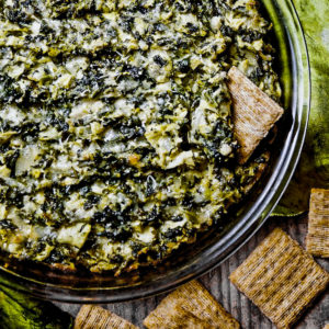 Cheesy spinach artichoke dip surrounded by crackers.