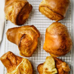Six big golden popovers on a rack.