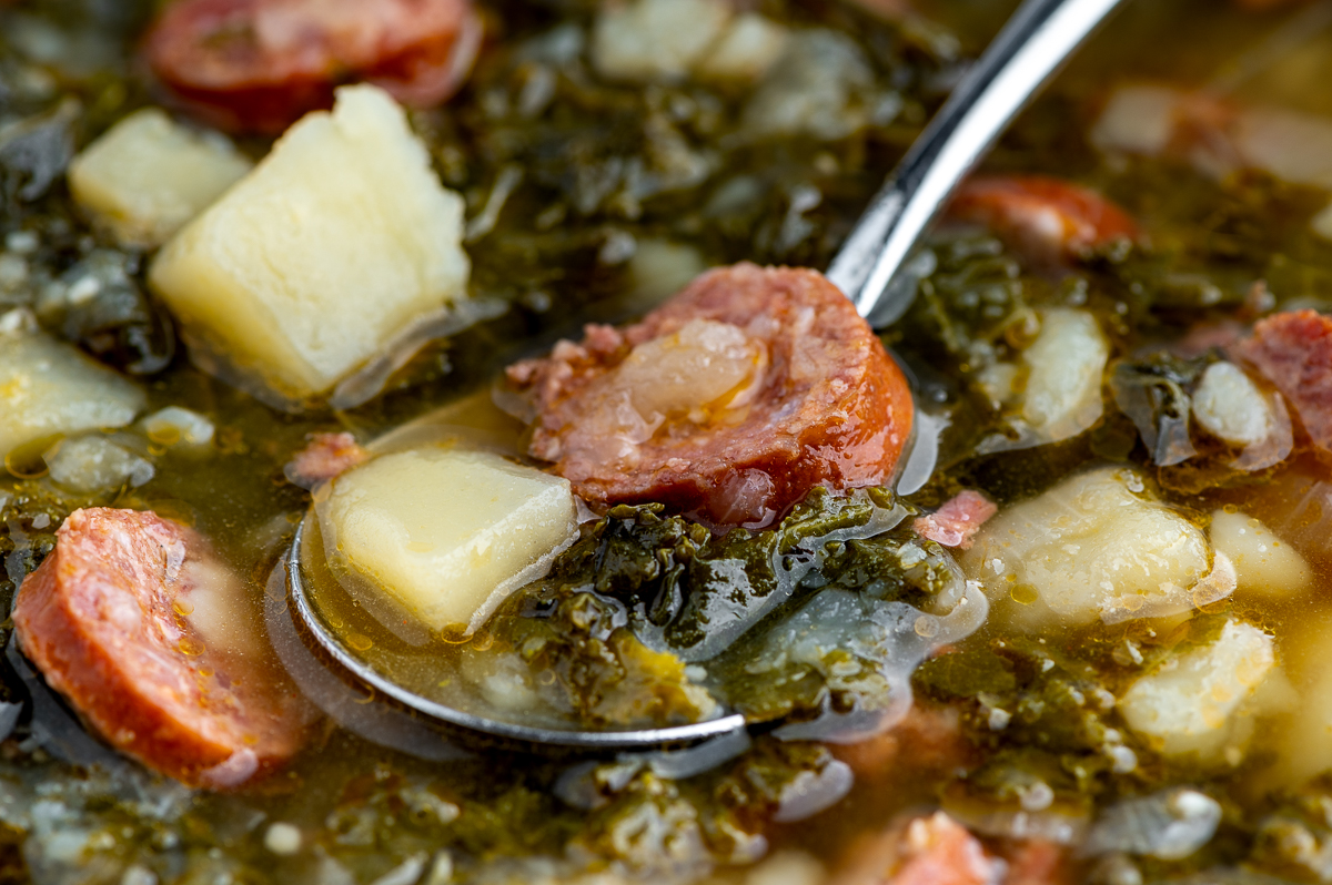 Potato, linguica, and kale soup on a spoon.