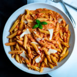A bowl of penne alla vodka with shaved Parmesan.