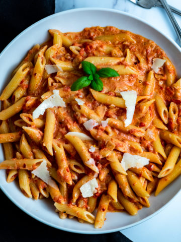 A bowl of penne alla vodka with shaved Parmesan.