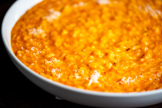 A closeup of a bowl of red pepper risotto.