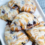 Five blueberry cream scones piled on a baking sheet.
