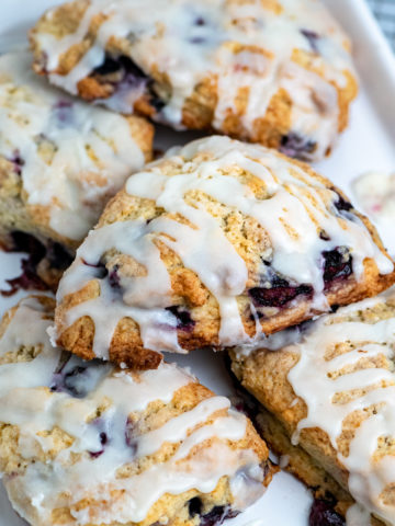 Five blueberry cream scones piled on a baking sheet.