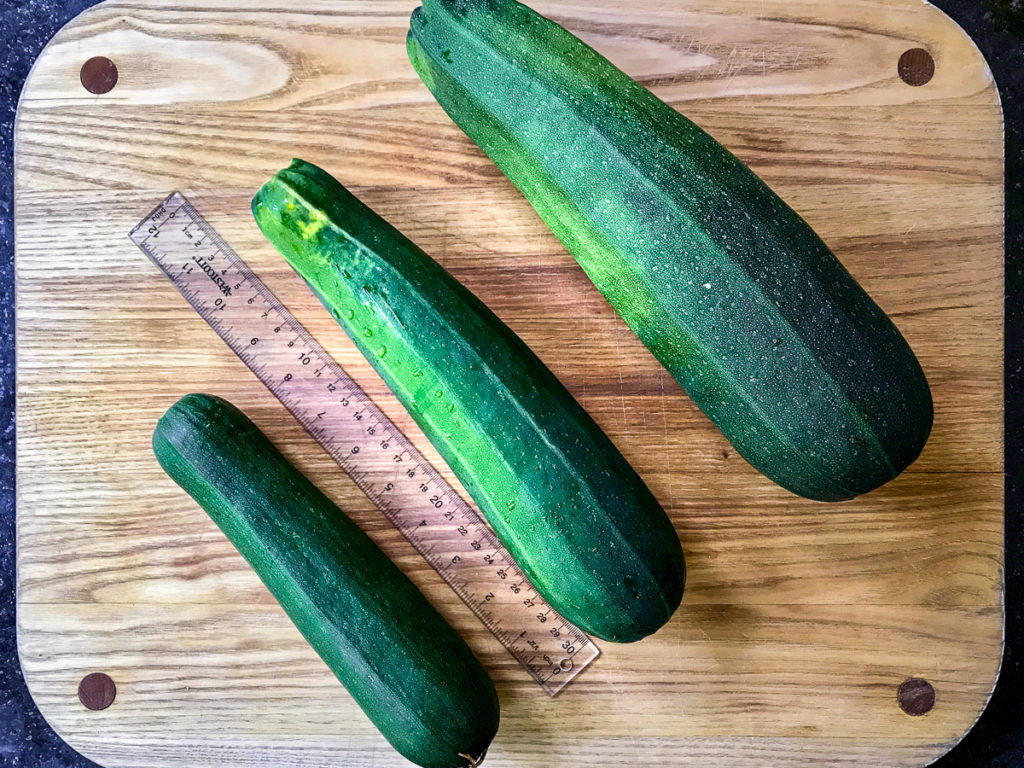 Different sized zucchini on a cutting board.