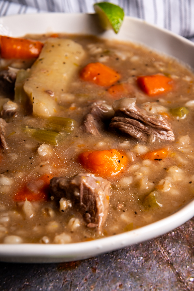 Beef barley soup in a white bowl.