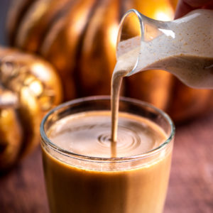 Pumpkin spice creamer being poured into a cup of coffee.