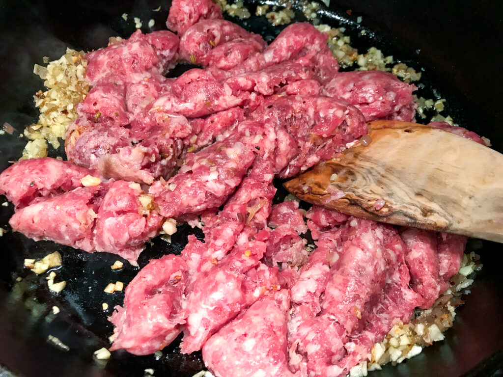 Breaking up sausage in a skillet.