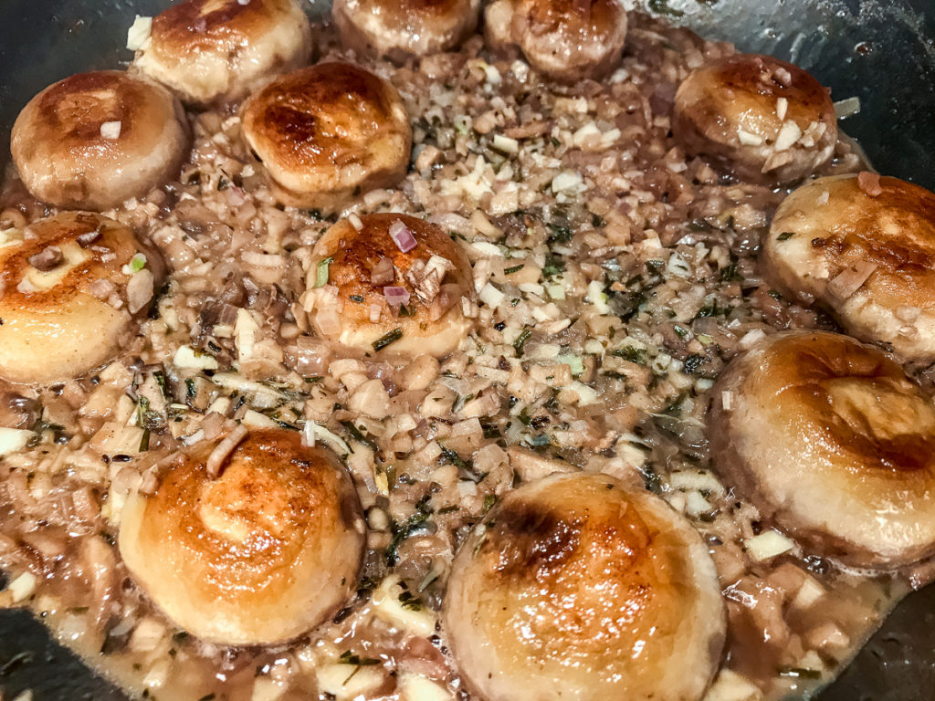Sautéing shallots, mushroom stems, and garlic with button mushrooms.