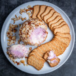 A port wine cheese ball coated in almonds surrounded by crackers.