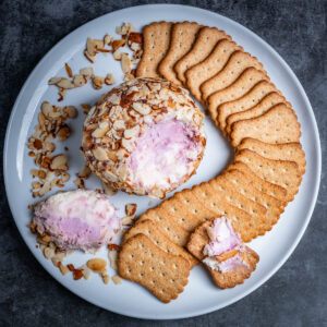 A port wine cheese ball coated in almonds surrounded by crackers.