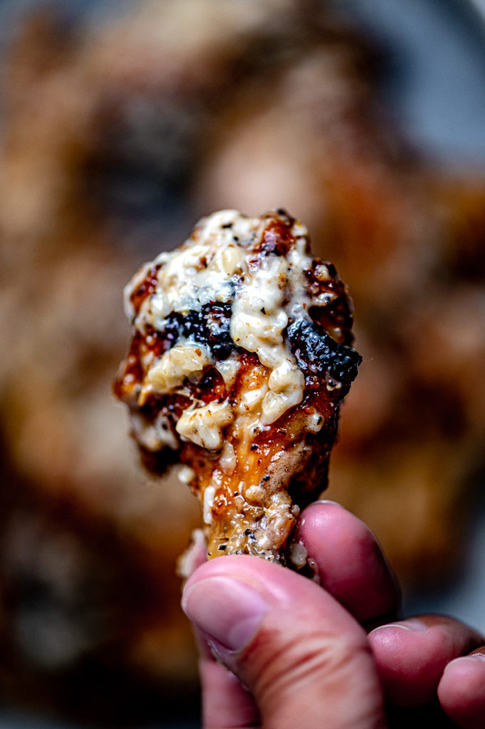 A closeup of a wing coated in garlic Parmesan sauce.