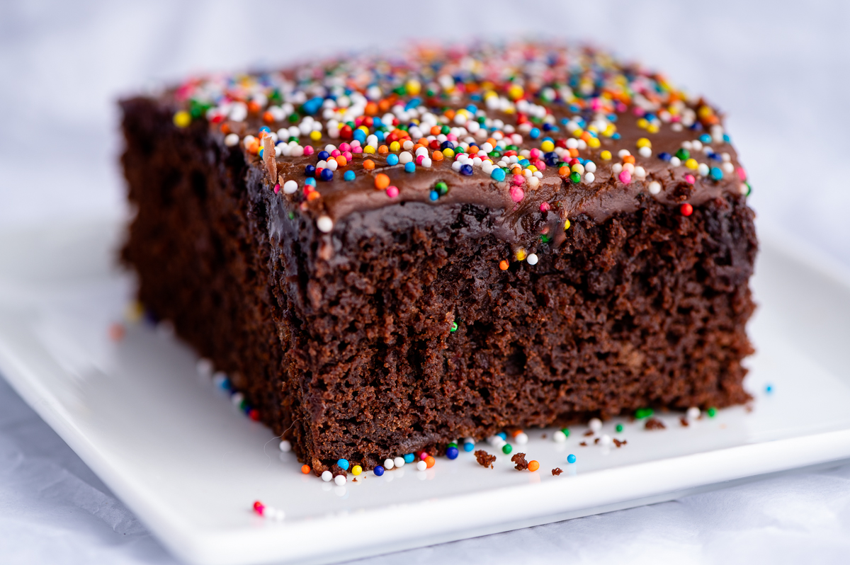 A slice of chocolate sheet cake topped with sprinkles.