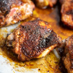 A closeup of a roasted chicken thigh coated with coffee rub.