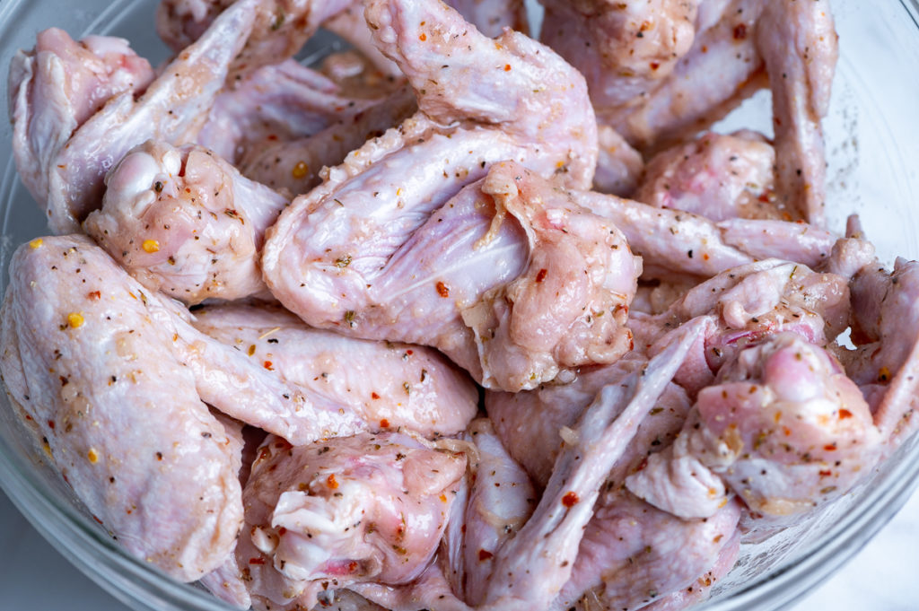 Chicken wings marinating in a bowl.