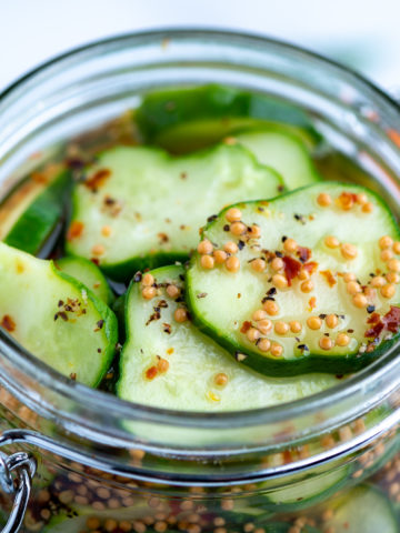 Kirby cucumbers sliced in a jar covered in pickling brine.
