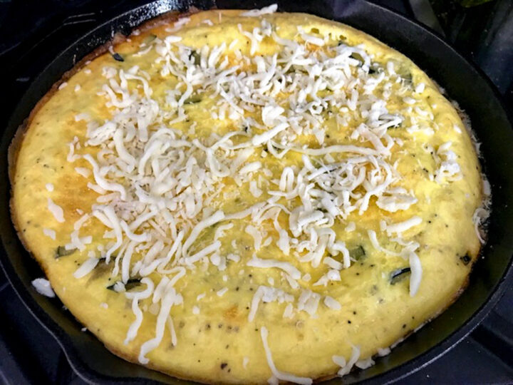 Adding cheese on a baked zucchini frittata.