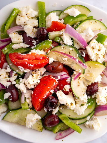 A white plate of Greek salad.