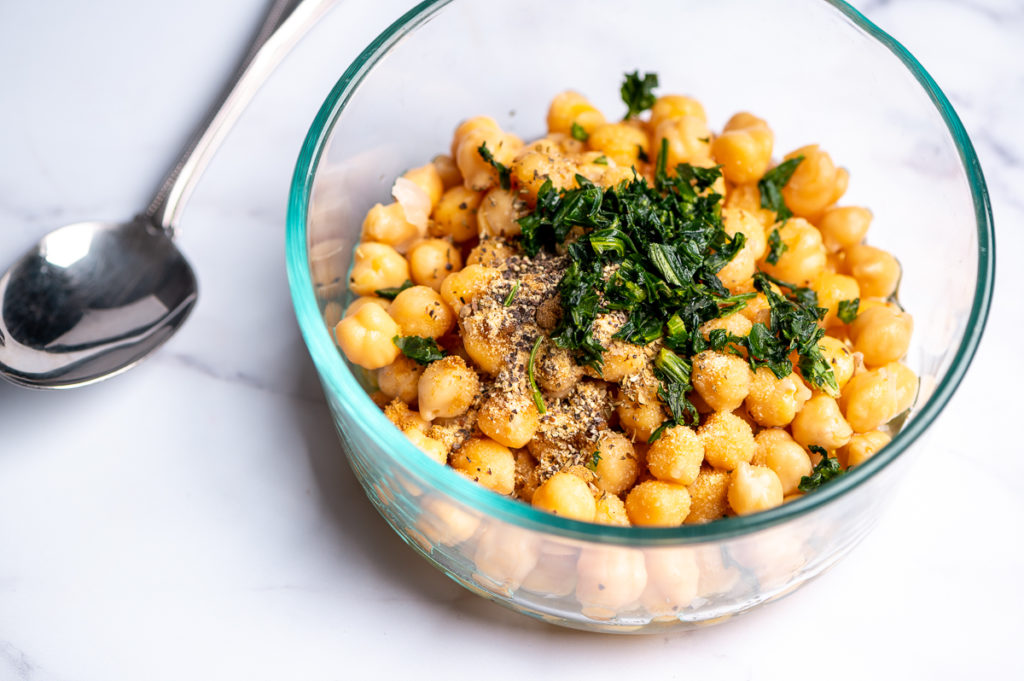 Chickpeas in a bowl with chopped parsley on top.