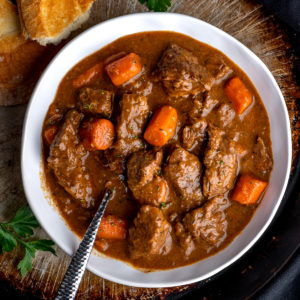 A white bowl of Guinness beef stew with crusty bread.