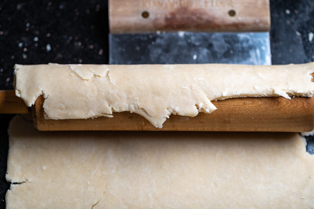 Rolling a pie crust onto a rolling pin.
