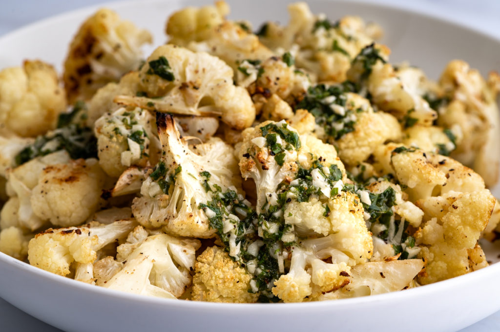 Cauliflower florets in a bowl with lemon garlic dressing poured on top.