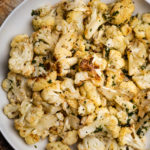 Roasted cauliflower tossed with lemon garlic dressing in a white bowl.