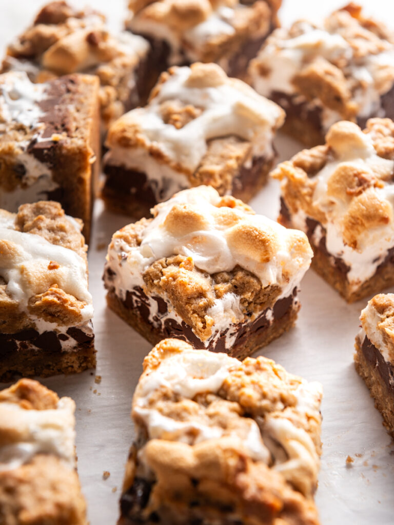 S'mores Bars with a chewy graham cookie base followed by a thick layer of chocolate, then topped with two types of marshmallows. Each bite is reminiscent of a campfire treat. #smores #smoresbars #bars #desserts | @thegeneticchef