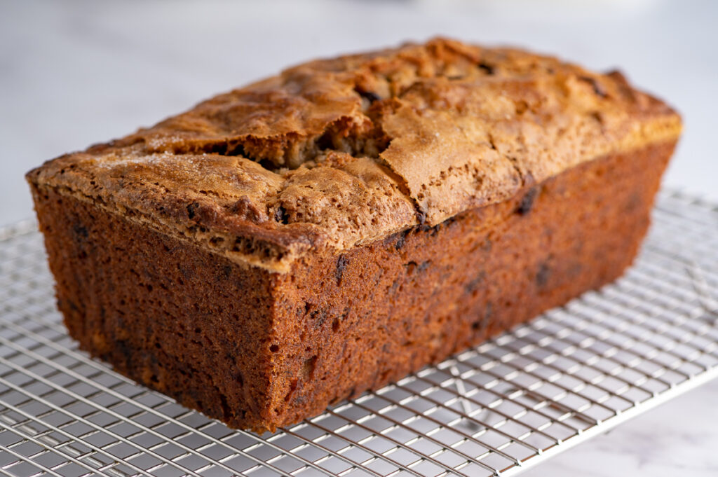 A loaf of chocolate walnut banana bread cooling on a rack.