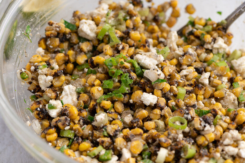Mixing the corn, feta and scallions in a bowl.