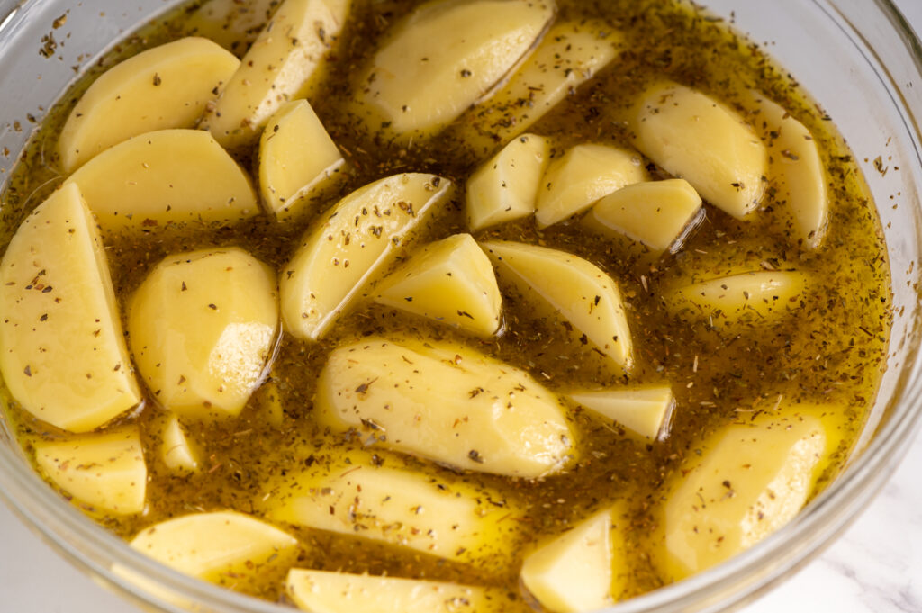 Potatoes covered with an oil dressing in a bowl.