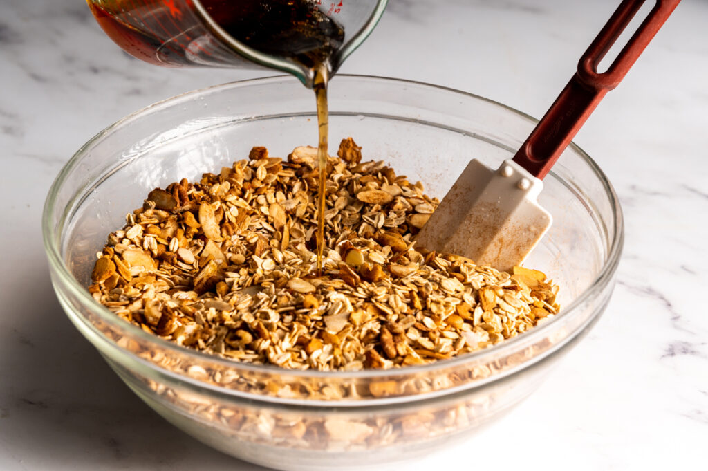 Adding maple syrup to granola ingredients.