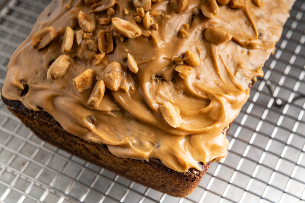 Peanut butter banana bread with peanut butter icing and chopped peanuts.