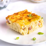 A slice of ham and cheese breakfast casserole on a dish.
