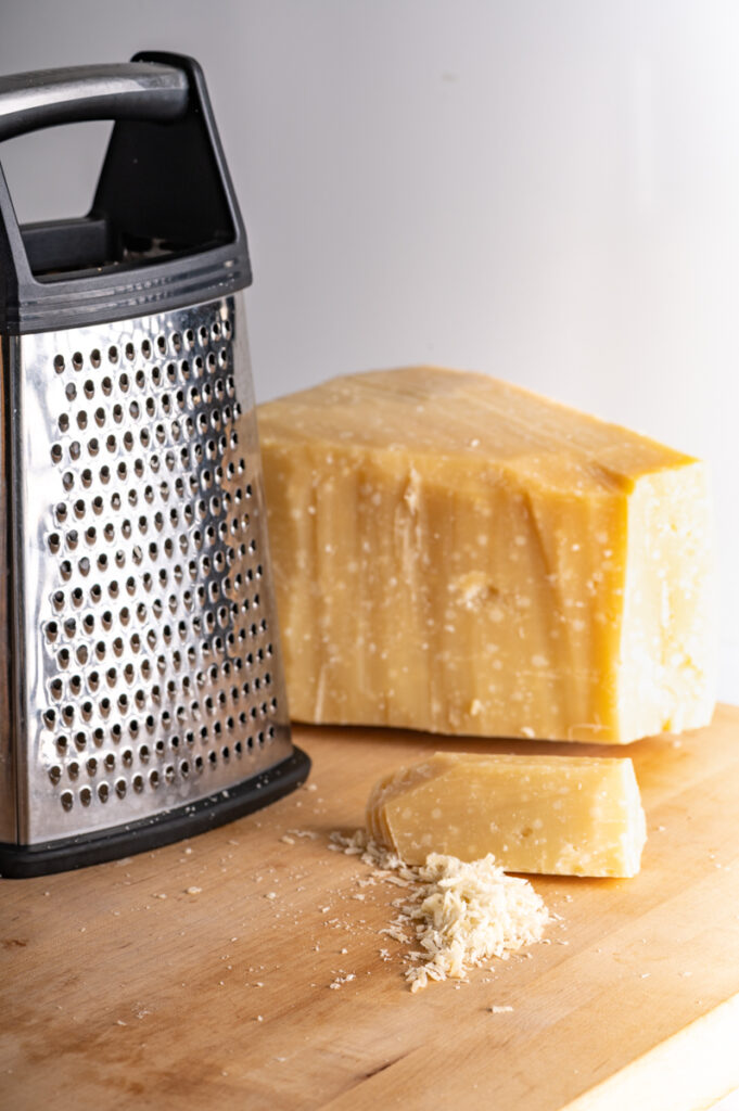 A block of Parmesan cheese with a grater.