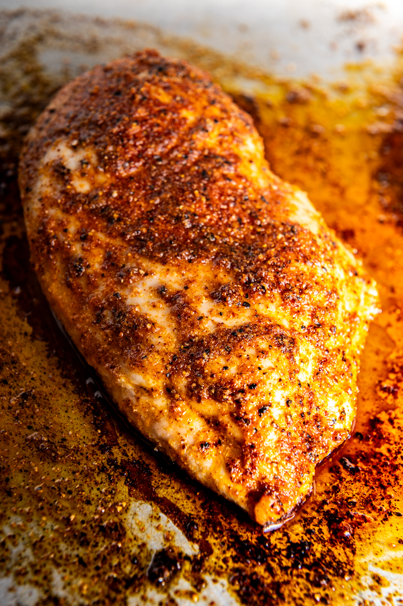 A seasoned chicken breast baked on a baking sheet.