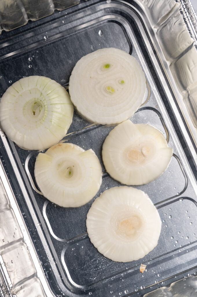 Thick slices of onions on the bottom of a foil pan.