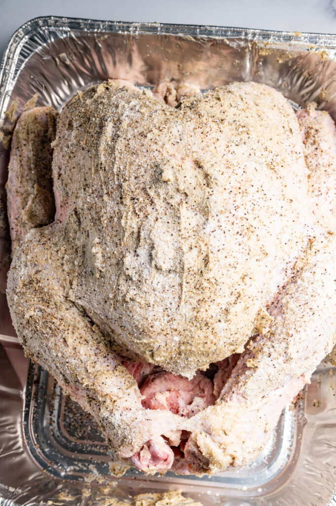 A whole turkey coated with butter and dried herbs.