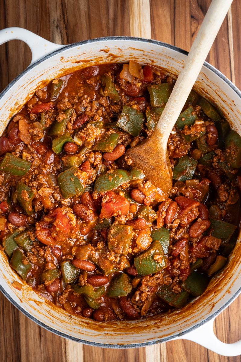 A pot of chili with peppers, beans, and tomatoes.