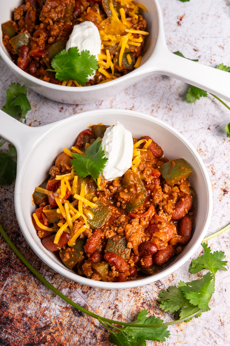 A bowl of chili topped with sour cream and cheese.